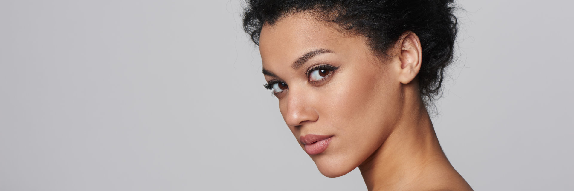 A profile of woman with tied up dark hair exposing her nicely shaped ear.