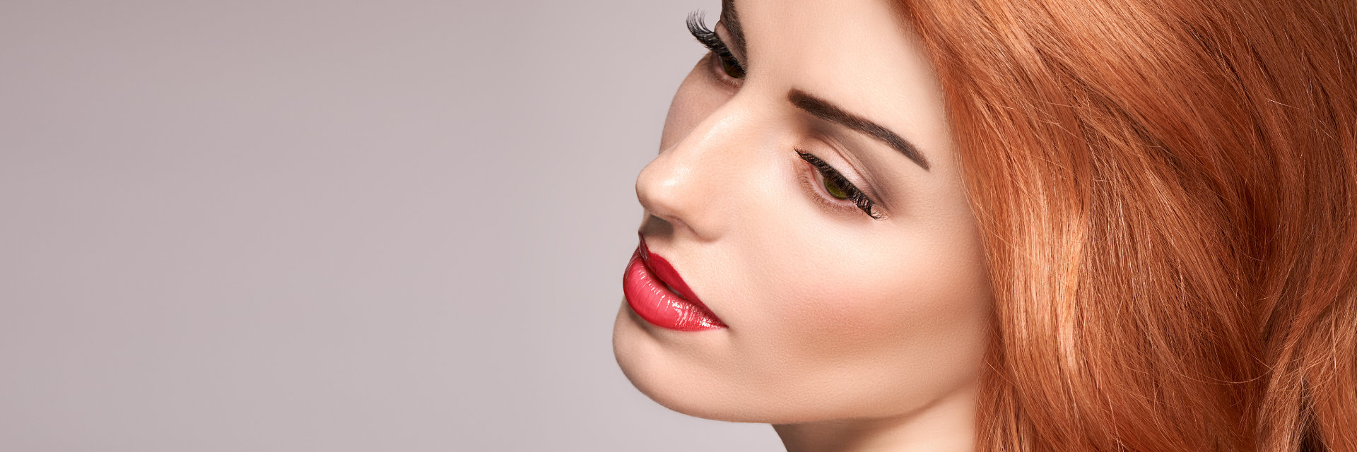 face of a beautiful re-haired woman with long lashes and red lips.