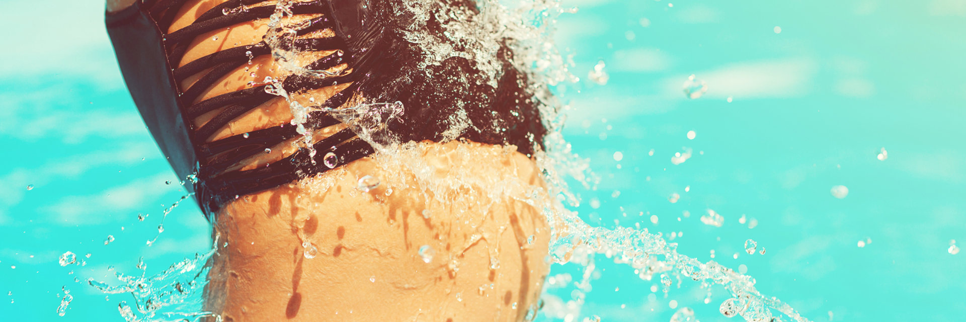 Butt of a woman in black bikini getting out of a swimming pool.