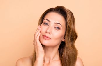 Youthful mature woman touching her cheek.