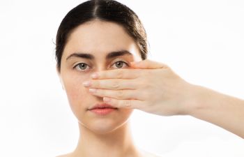 Young woman covering her nose with her hand.